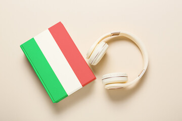 Modern headphones and book on light background. Concept of studying Italian language