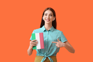 Young woman with earphones and book on orange background. Concept of studying Italian language