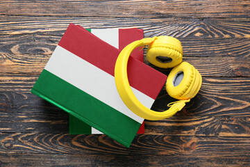 Modern headphones and books on wooden background. Concept of studying Italian language
