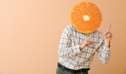 Dancing man with ripe tangerine instead of his head on beige background