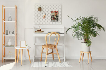 Interior of light office with workplace, pegboard and shelving unit