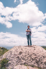 Latino student on top of a hill with his arms crossed and looking at camera