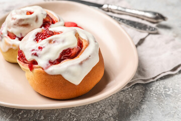 Plate with strawberry cinnamon rolls and cream on grunge background, closeup