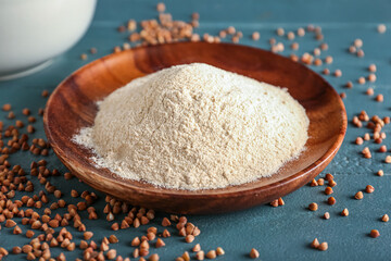 Plate of flour and buckwheat grains on dark wooden background, closeup