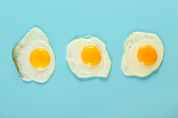 Tasty fried eggs on blue background