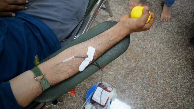 Blood donor at Blood donation camp held with a bouncy ball holding in hand at Balaji Temple, Vivek Vihar, Delhi, India. Also concept image for World blood donor day on June 14 every year