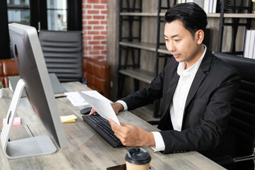 Portrait of business man using computer at workplace in an office. positive business man smiling looking at paper.