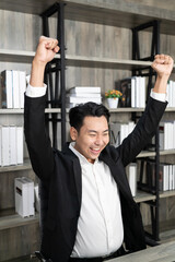 Fototapeta na wymiar Employee employer employment entrepreneur executive man in formalwear raised hands fists up sit on chair. Emotional guy feeling glad and happy as he's great success, finishes successful business.
