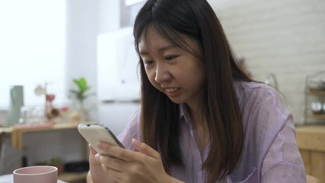 asian lady is shouting with eyes flying open upon receiving a surprising notification on her phone and keeping tapping on the screen after eagerly swiping down.