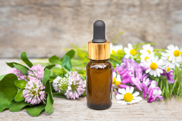 Glass brown bottle with essential oil and wildflowers on a wooden background. Aromatherapy and herbal medicine.