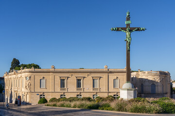 Urban landscape view of historic bronze calvary and beautiful ancient stone buildings on place Giral, Montpellier, France, on a bright blue sky summer morning