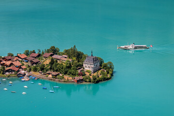 High view over the village of Iseltwald at the turquoise Brienz Lake with a tour ship on the lake, Switzerland.