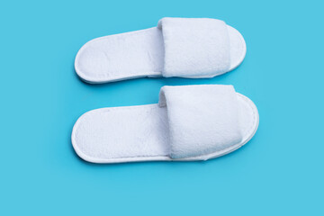 Hotel slippers on blue background. Copy space