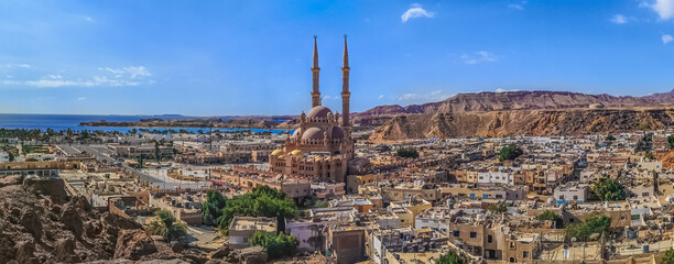 Widescreen panorama of the Old Market in Sharm El Sheikh with the Al Sahaba Mosque in the center and the Red Sea on the horizon. Aerial view of an Egyptian resort - obrazy, fototapety, plakaty