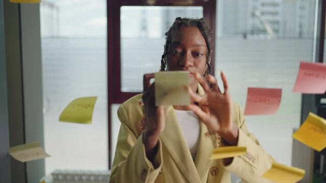 African American Business Woman Using Sticky Notes Brainstorming Problem Solving Strategy On Glass Whiteboard, Leader Woman Planning Project On Post It Sticky Notes In Office.