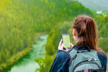 Young woman uses smartphone at mountains and using travel app or map during her hike. Empty space for text - Powered by Adobe