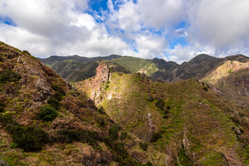 Obraz premium Panoramic view on the mountains of Anaga massif between Afur and Taganana on Tenerife, Canary Islands, Spain, Europe, EU. Hill landscape in UNESCO Anaga biosphere rural park. Clouds emerging. Hiking