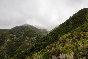 Fototapeta na wymiar Panoramic view on the cloud covered mountains of Anaga massif between Afur and Taganana on Tenerife, Canary Islands, Spain, Europe, EU. Hill landscape in UNESCO Anaga biosphere park. Tropical forest