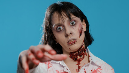 Undead zombie woman with bloody and deep wounds on neck prowling at camera. Terrifying evil looking...