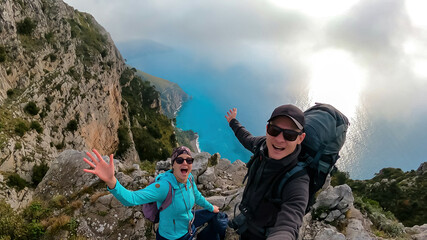 Couple taking selfie with scenic view from a hiking trail on coastal driving road of beautiful Amalfi Coast, Campania, Italy, Europe. Riviera coastline at Mediterranean sea. Road near Positano