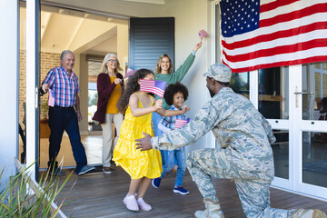 Multiracial excited multigeneration family with flag of america welcoming army soldier in house
