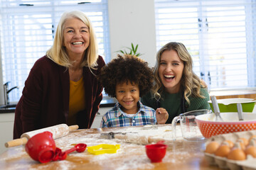 Portrait of cheerful multiracial multigeneration family preparing food on messy table in kitchen