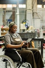 Female worker with disability using digital tablet to check items during her work in factory