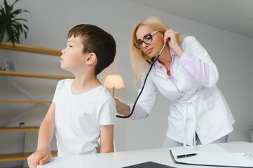 Fototapeta premium Pediatrician doctor examining little boy's heart beat and lungs to check for problems