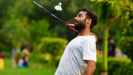 man playing badminton racket with shuttlecock in park