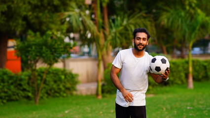 man holding football in green park