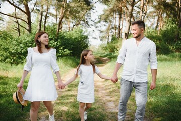 Fototapeta premium Happy pregnant couple with daughter in summer nature.