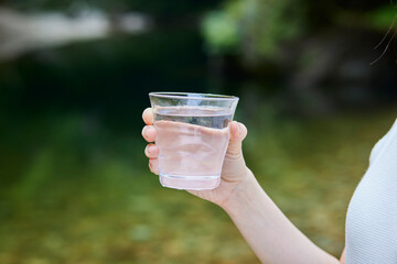 自然の中でコップに入った水を持つ女性