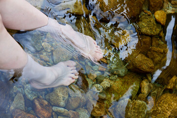 川に浸かる若い女性の足元