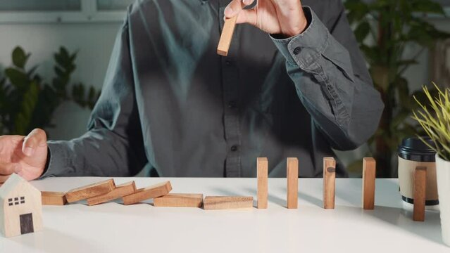 Business risk planning. Man hand pick up one of wood block from many row falling wooden block like domino effect for stopping business risks with strategy by efficient prevent management