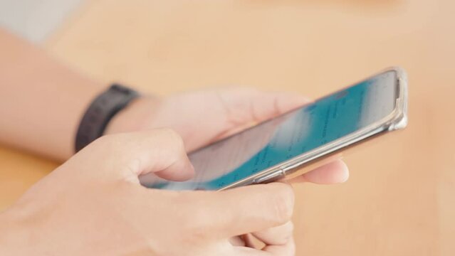 Hand of woman using application on smartphone she reading mail on social media at wooden teble, finger of happy female slide modern mobile phone screen, online internet searching