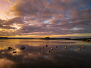 Aerial sunrise waterscape with boats, reflections and cloud filled sky