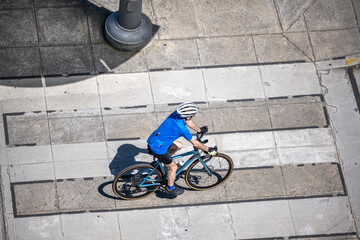 Cyclist in a bicycle outfit as active lifestyle lovers rides along a dedicated bike path on the street of a summer urban city