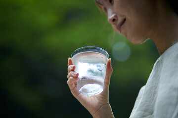自然の中でコップに入った水を持つ女性