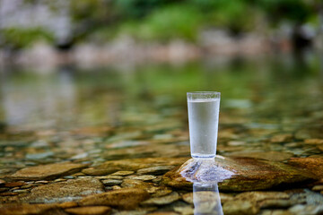綺麗な川に置かれた水の入ったグラス