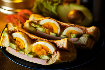 木製のテーブルにホットサンドとコーヒーとランタンの夜のキャンプ飯