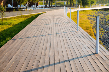 A pedestrian road made of boards, a wooden path, a place for walking in the park, a modern city recreation park, the lines go up.