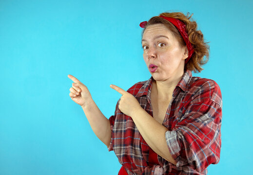 Pin-up woman in a plaid shirt shows on a blue background. Beautiful forty-year-old woman on a blue background. adult woman