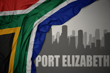 abstract silhouette of the city with text Port Elizabeth near waving colorful national flag of...