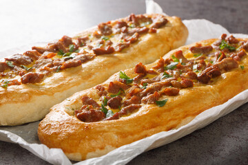 Macedonian pastrmajlija pie, made with with hot peppers, chunks of meat and egg, lard and a crispy layer of crust closeup on the parchment on the table. Horizontal