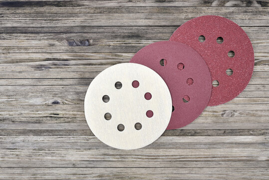 Round Sandpaper Discs For Random Orbital Sander. Adhesive Sanding Disks For Palm Sander Machine On A Wooden Background.