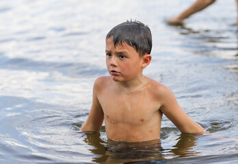 a boy swims in a pond in summer