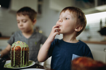 Brothers decorating Easter cakes with glace icing eating sugar topping. Image with selective focus