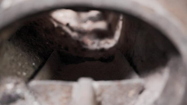 An iron shovel is stuffed into the ashes of a rural stove. First-person view