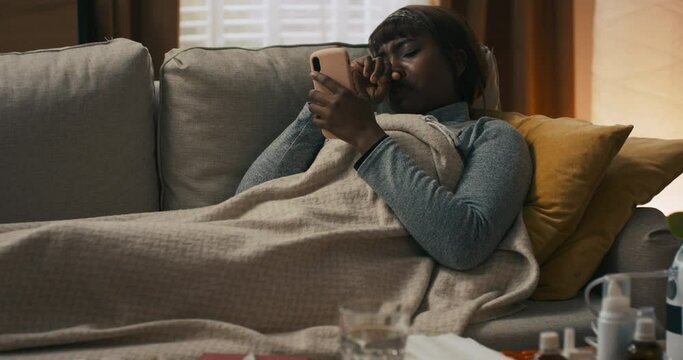 A dark-haired woman is lying in bedroom resting after a severe illness. For several days, the girl has had a cold and has symptoms of fever. There is a flu in the house.