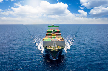 Aerial front view of a loaded container cargo vessel traveling over the ocean with good weather